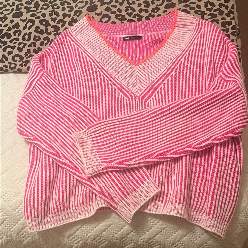 Stylish V-neck sweater with vibrant pink and white stripes.